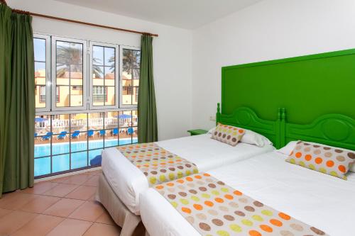 a hotel room with two beds and a pool at Apartamentos Maxorata Beach in Corralejo