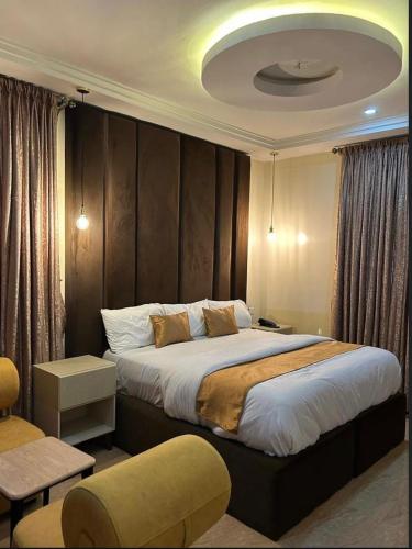a bedroom with a large bed and a chair at Maas Nightingale Apartments in Port Harcourt