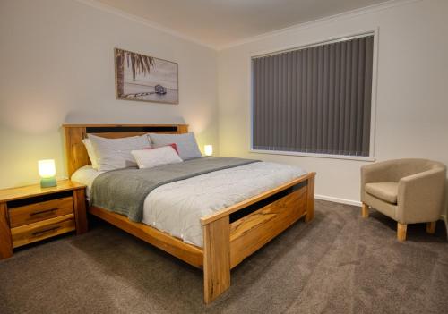 a bedroom with a bed and a chair and a window at Sorell Gateway Villa in Sorell