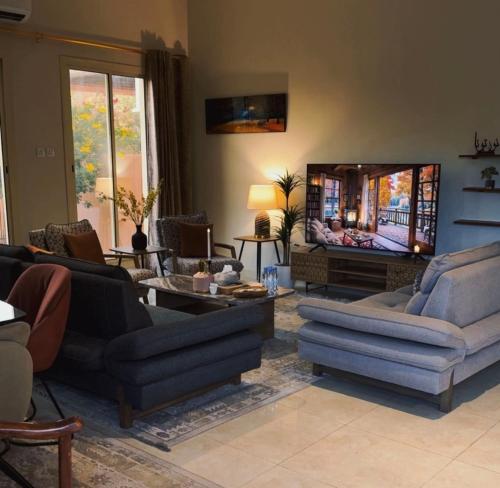 ein Wohnzimmer mit Sofas und einem Flachbildfernseher in der Unterkunft فيلا بمزرعة in Al-'Ula