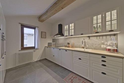 Una cocina grande con gabinetes blancos y una ventana. en Attic Lake View with Free Parking, en Silvaplana