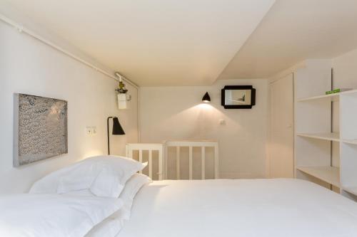 a white bedroom with a white bed and shelves at Opéra Septembre in Paris