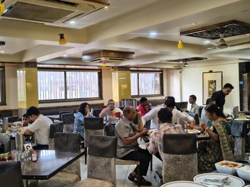 eine Gruppe von Menschen, die an Tischen in einem Restaurant sitzen in der Unterkunft Royale Heritage in Nashik