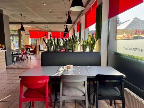 een eetkamer met een tafel en rode stoelen bij Ibis Katowice - Zabrze in Zabrze