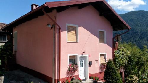 a pink house with mountains in the background at Apartment Pri Bricu in Kobarid