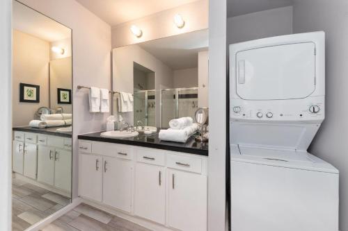 a white bathroom with two sinks and a large mirror at Reside Houston Downtown, a Wyndham Residence in Houston