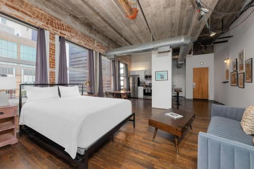 a bedroom with a large white bed and a couch at Reside Houston Downtown, a Wyndham Residence in Houston
