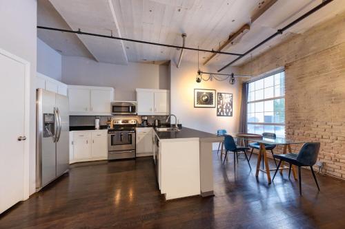 a kitchen with white cabinets and a table with chairs at The District at Hogg Palace, A Wyndham Hotel in Houston