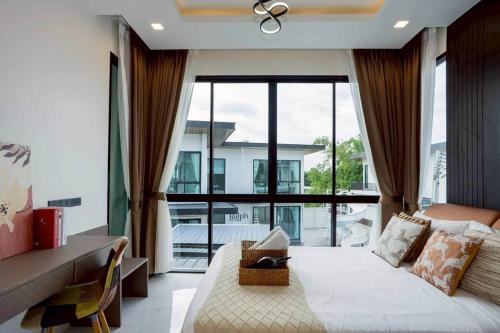 un salon avec un lit et une grande fenêtre dans l'établissement Walters House Pool Villa Pattaya, à Ban Huai Yai