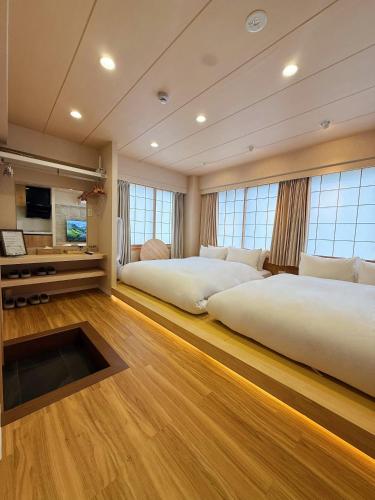 two beds in a room with wood floors and windows at Rakuyu asakusa in Tokyo