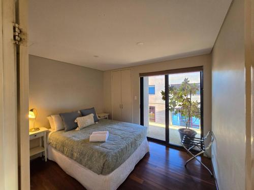 Un dormitorio con una cama y una puerta corrediza de vidrio. en Sunset on Fearn, lovely 2 bedroom apartment, en Margaret River Town