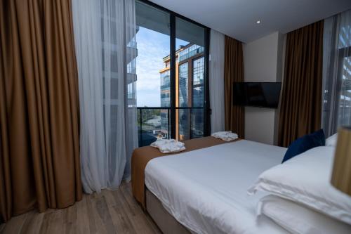 a hotel room with two beds and a large window at New Wave Apart-Hotel in Batumi