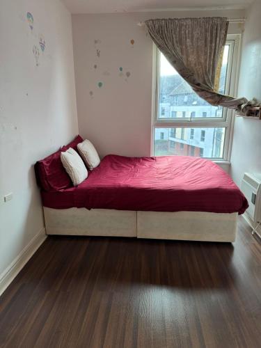 een slaapkamer met een bed met een rode deken en een raam bij Charming Edinburgh Apartment with Electric Heating Free WiFi in Edinburgh