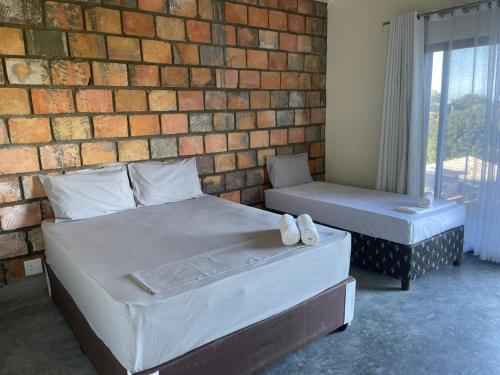 a bedroom with two beds and a brick wall at lodge3a in Ponta do Ouro