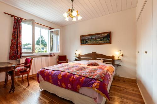 a bedroom with a bed and a table and a window at Chambres d'hotes du Prieur in Léognan