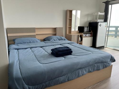 a large bed with a blue comforter in a bedroom at Rayong Condo Chain Phe in Ban Pak Khlong Phe