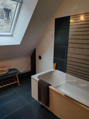 a bathroom with a bath tub in a attic at Appartement au port Le Mont-Saint-Michel in Dinan
