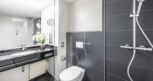 a bathroom with a toilet and a sink and a shower at PLAZA Premium Darmstadt in Darmstadt