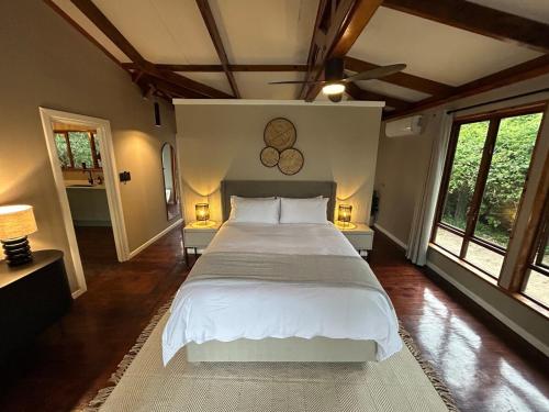 a bedroom with a large white bed with two lamps at The Cabin Luxury Safari Villa in Somerset