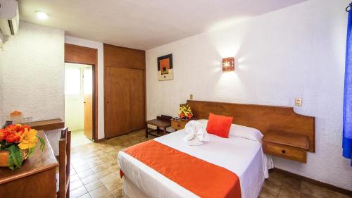 a hotel room with a bed with orange and white sheets at Hotel Hacienda Vallarta - Playa Las Glorias in Puerto Vallarta