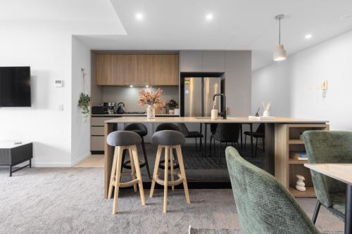 an open kitchen and dining room with a table and stools at West End 2BR Gem with Rooftop Pool, Balcony & Parking in Brisbane