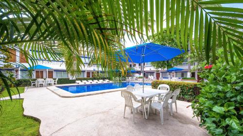 a table with chairs and a blue umbrella next to a pool at Hotel Hacienda Vallarta - Playa Las Glorias in Puerto Vallarta