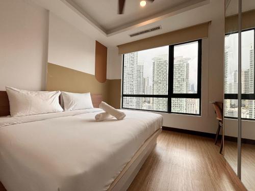 a bedroom with a large white bed and large windows at Casa Residency Bukit Bintang by PILLOWTALKS in Kuala Lumpur