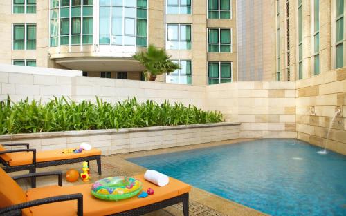 a pool with a table and chairs next to a building at Sofitel Abu Dhabi Corniche in Abu Dhabi