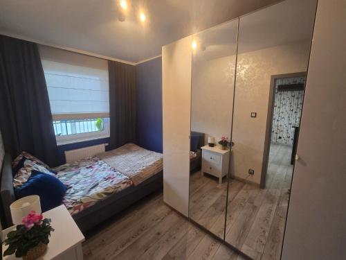 una piccola camera da letto con un letto e uno specchio di Apartament Ami a Płock