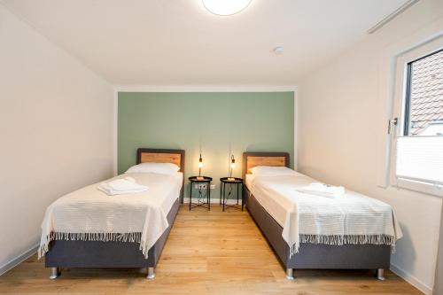 two beds in a room with two windows at CharmÖHR Homes in Öhringen