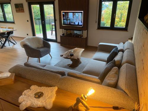 Una sala de estar con un sofá y un televisor. en La Roanneuse - Cosy Chalet, en Francorchamps