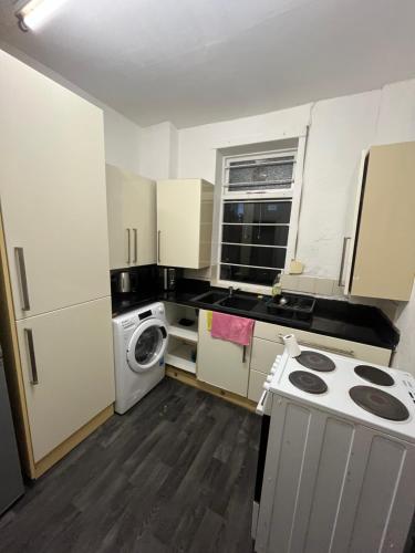 a small kitchen with white cabinets and a washer and dryer at Cooperate home2 in Oldham