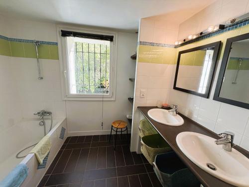 Un baño con dos lavabos y una bañera. en Bastide Terrieu - domaine avec piscine et terrain de boules, climatisation, en Saint-Mathieu-de-Tréviers