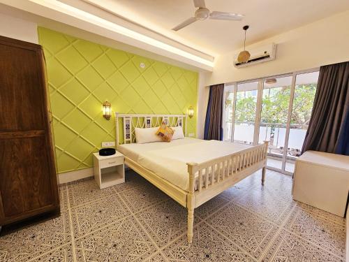een slaapkamer met een wit bed en een groene muur bij Spacious Condo with Pool View in Anjuna