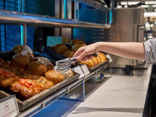 a person is reaching for a tray of bread at Sindhorn Kempinski Hotel Bangkok in Bangkok