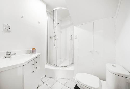 ein weißes Badezimmer mit Dusche und Toilette in der Unterkunft Spacious 3-Bedroom Retreat Near Airport & City in Auckland