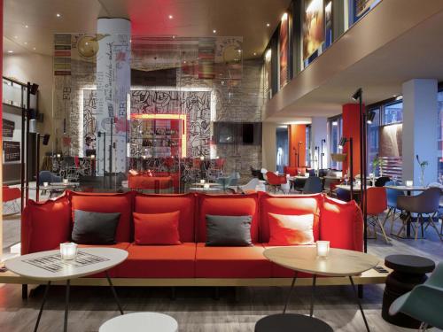 a red couch in a restaurant with tables at Ibis Den Haag City Centre in The Hague