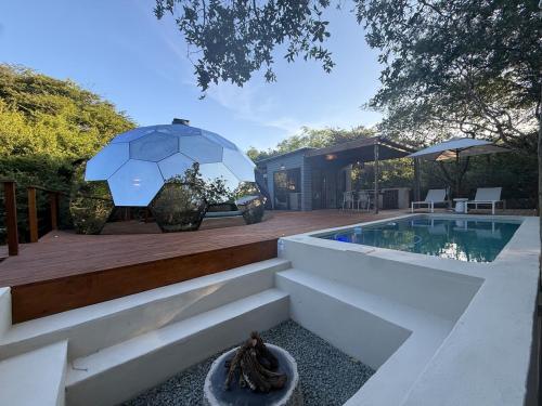 a house with a swimming pool and an umbrella at The Dome Luxury Safari Villa in Hluhluwe