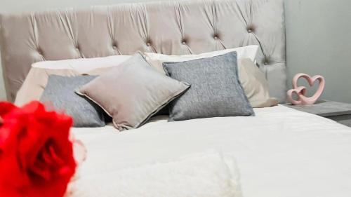a bedroom with a white bed with pillows and a pink rose at The Perazim Place in Hazyview