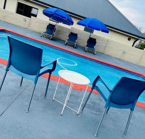 a table and chairs and umbrellas next to a swimming pool at The Perazim Place in Hazyview