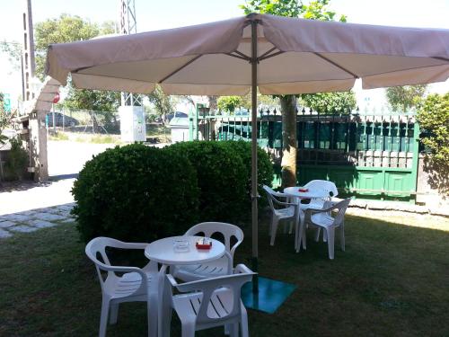 two white tables and chairs under an umbrella at Hotel Maruxa in A Lanzada