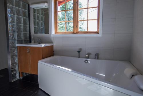 a bath tub in a bathroom with a window and a sink at Maristuen Fjellferie in Borgund