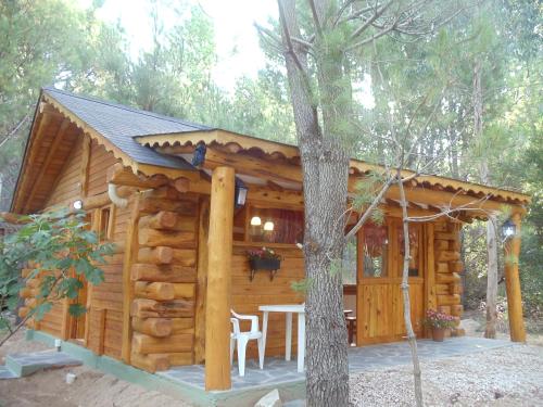 una cabaña en el bosque con mesa y sillas en Patagonia Playa Cielo en Mar de las Pampas