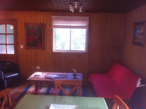 a living room with a red couch and a table at Cabañas Rahue in Vilches