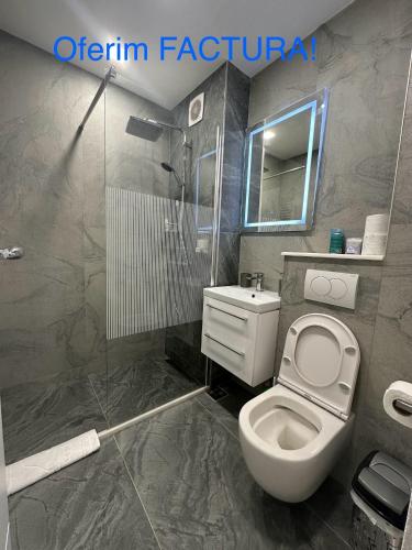 a bathroom with a white toilet and a shower at Apartament Ultra Central 4 in Hunedoara