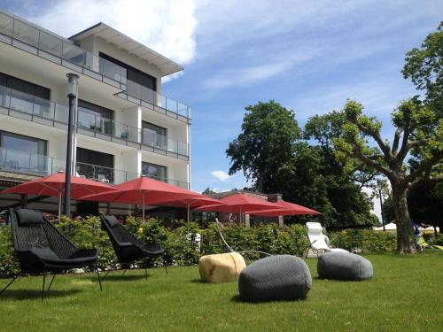 a lawn with chairs and umbrellas in front of a building at Seehotel Kressbronn in Kressbronn am Bodensee