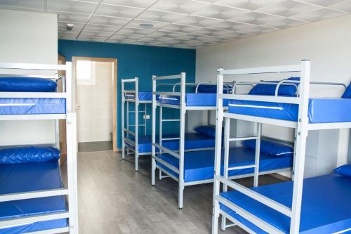 een groep stapelbedden in een kamer met blauwe muren bij De Camino in Arzúa