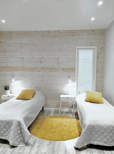 two beds in a bedroom with wooden walls at Villa Pinja in Kalajoki