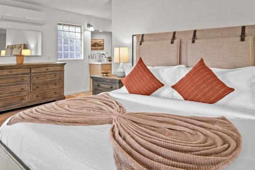 une chambre avec un grand lit blanc avec des oreillers orange dans l'établissement Sugarloaf House Private Trail Access Hot Tub Game Room OMG Red Rock Views, à Sedona
