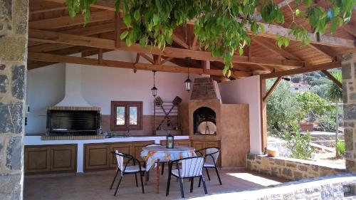 an outdoor kitchen with a table and chairs and a fireplace at House of Polymnia in Sissi